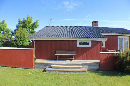 a red building with a bench in front of it at The Little Red Cabin Near Blåvand! in Blåvand