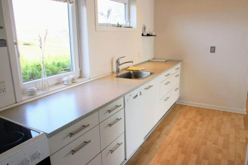 a kitchen with white cabinets and a sink and a window at The Little Red Cabin Near Blåvand! in Blåvand