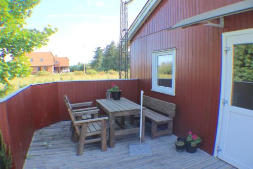 a patio with a wooden table and bench on a red building at The Little Red Cabin Near Blåvand! in Blåvand