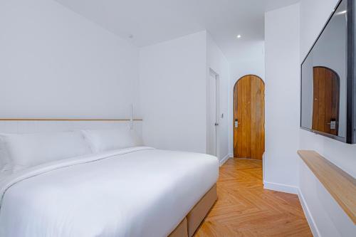 a bedroom with a white bed and a wooden floor at Casa 33 Hatyai in Hat Yai
