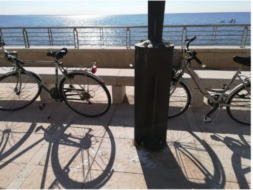 twee fietsen geparkeerd naast een paal naast de oceaan bij Cosy Apartment in Grado
