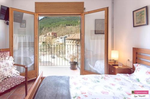 a bedroom with a bed and a door to a balcony at Apartament Tritó - Rústico y acogedor con vistas - 2p in Guardiola de Berguedà