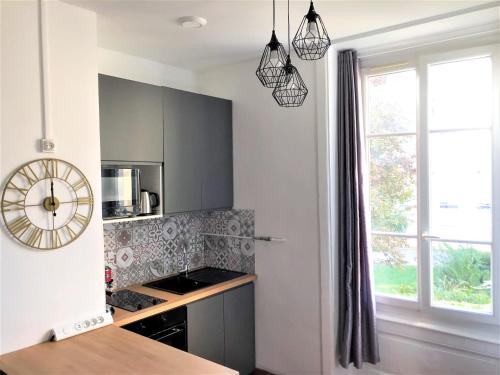 a kitchen with black cabinets and a clock on the wall at Côté Cour Lyon Part Dieu in Lyon