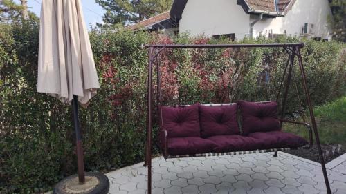 a purple couch sitting on a swing next to an umbrella at Kuća Zlatica in Palić