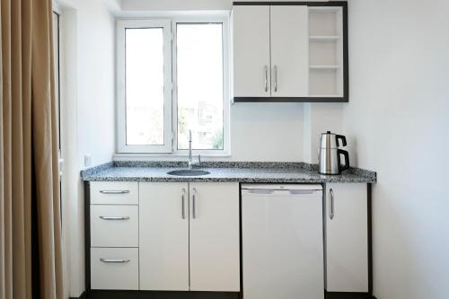 a kitchen with white cabinets and a sink and a window at Marvida Happy Suites in Antalya