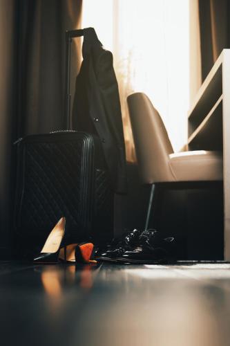 a room with a suitcase on the floor and a chair at The Lamp Hotel & Spa in Norrköping