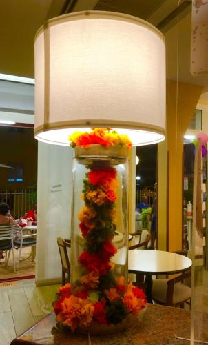 a vase filled with flowers on a table under a lamp at Hotel Alessi** Rimini in Rimini