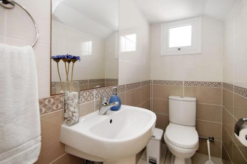 een badkamer met een wastafel, een toilet en een spiegel bij Villa Nissinia - Nissi Beach Area in Ayia Napa