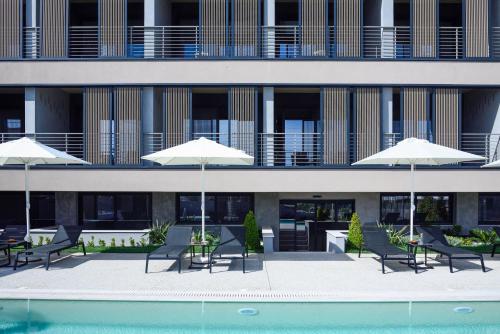 a building with chairs and umbrellas next to a pool at ANASSA BUTIK LIVING NIKITI in Nikiti