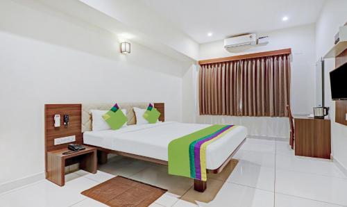 a bedroom with a large bed and a television at Treebo RJ Residency in Mysore