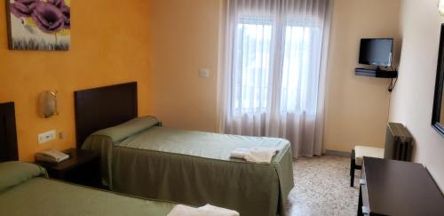 a hotel room with two beds and a window at Hotel Balfagón in Calanda