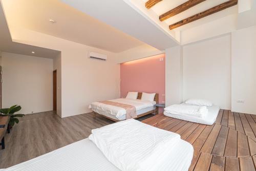 two beds in a room with wooden floors at 睡海邊包棟民宿 sleep on beach B&B in Suao