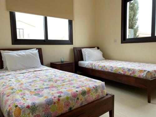 two beds in a room with two windows at Kyklades Resort & Spa in Paralimni