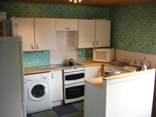 a kitchen with a washing machine and a washer at RoSE COTTAGE THREE BEDROOM HOUSE WITH PARKING in Carsphairn
