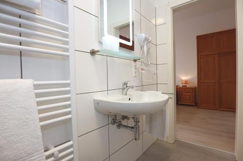 een witte badkamer met een wastafel en een spiegel bij Rössle Apart FeWo in Friedenweiler