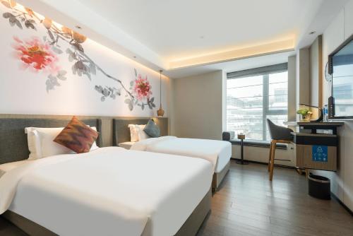 a hotel room with two beds and a television at Paco Hotel Canton Tower Pazhou-Free shuttle bus for canton fair in Guangzhou