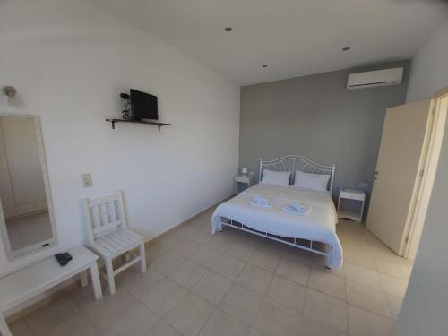 a bedroom with a white bed and a chair at Antonios 1 in Matala