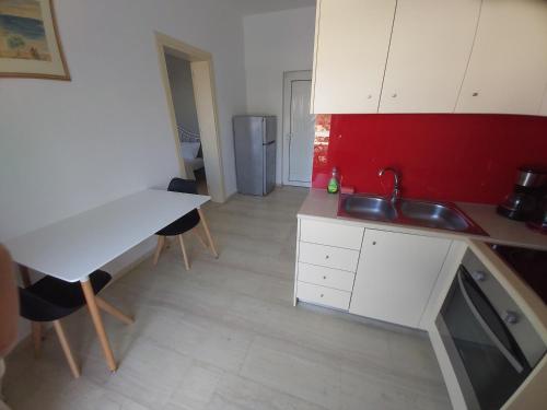a kitchen with white cabinets and a red wall at Antonios 1 in Matala