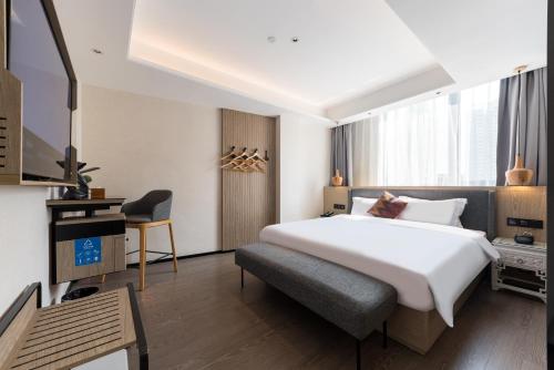 a bedroom with a large white bed and a chair at Paco Hotel Canton Tower Pazhou-Free shuttle bus for canton fair in Guangzhou
