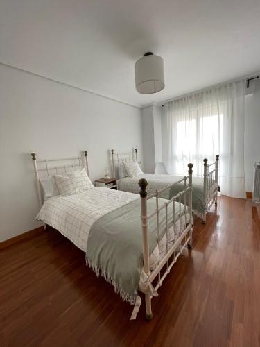 Zwei Betten in einem weißen Schlafzimmer mit Holzboden in der Unterkunft KEY HOUSE in Laguardia