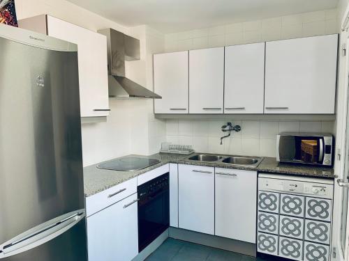 a white kitchen with white cabinets and a sink at Hauzify I Apartament Fortuny in Sant Feliu de Guixols