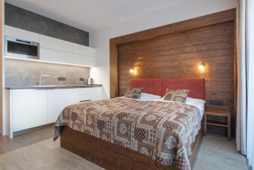 a bedroom with a bed and a wooden wall at Apartmán Sivý vlk Hrebienok Rezort in Smokovce