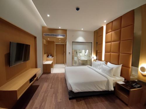 ラクナウにあるDamson Plumのベッドとテレビが備わるホテルルームです。