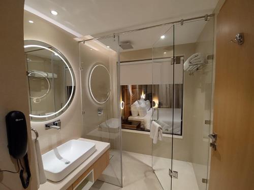 uma casa de banho com uma cabina de duche em vidro e um lavatório. em Damson Plum em Lucknow