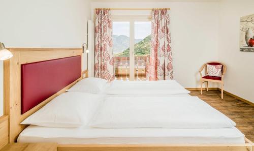 1 dormitorio con 2 camas y ventana en Rasnerhof Ferienwohnung Talblick, en Lagundo