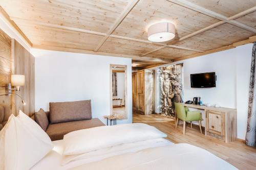 a bedroom with a bed and a couch and a desk at Hotel Thurnerhof in Saalbach Hinterglemm