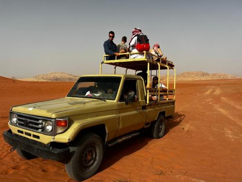 a group of people riding in the back of a truck in the desert at Wadi Rum Desert Adventures in Wadi Rum