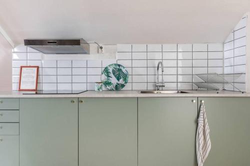 - une cuisine avec des murs carrelés blancs et un évier dans l'établissement Pensionat Enehall, à Båstad