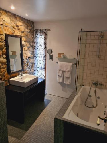 a bathroom with a tub and a sink and a mirror at Posada Los Calderones in Santillana del Mar