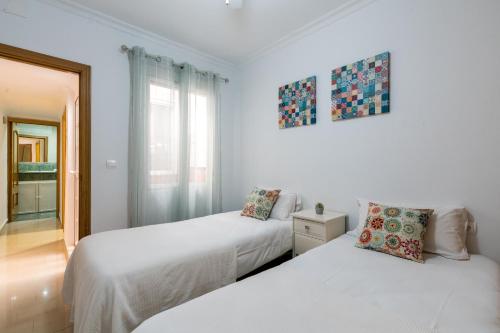 セビリアにあるHoli-Rent Saladoの白い壁の部屋にベッドが2つある