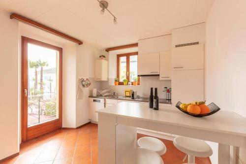 una cucina con armadi bianchi e bancone con sedie di Casa al Sole - Bellissimo appartamento con terrazza e vista lago a Minusio