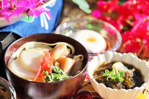 那覇市にある沖縄逸の彩ホテルの花が飾られたテーブルの上に2つのボウルの食べ物