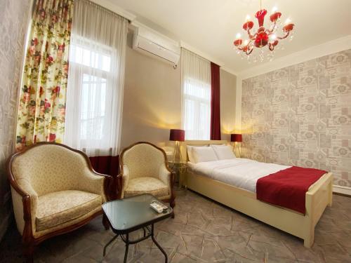 a bedroom with a bed and two chairs and a chandelier at Hotel Orange Kutaisi in Kutaisi