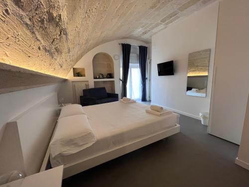 - une chambre blanche avec un lit et une chaise dans l'établissement Il Giramondo Suite&Room, à Matera