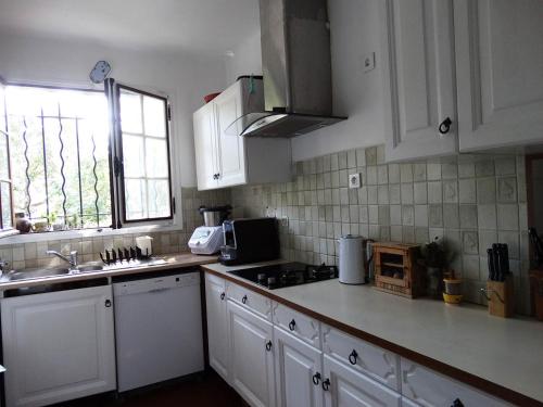 cocina con armarios blancos, fregadero y ventana en Chambre dans propriété La Croix du Sud, en Le Pradet