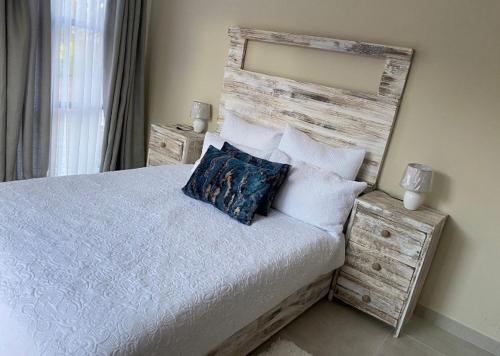 a bedroom with a bed with a wooden headboard and pillows at Lime Court two in Pretoria