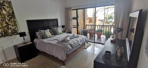 um quarto com uma cama grande e uma varanda em Cycadales Villa em Sabie