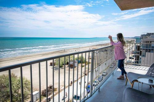 a woman standing on a balcony looking at the beach at Lemon Cliff Luxury B&B in Mamaia Nord