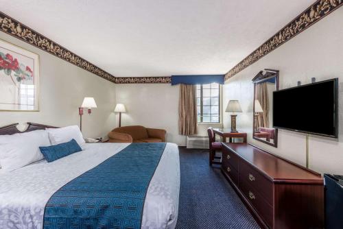 a hotel room with a bed and a flat screen tv at Days Inn & Suites by Wyndham Youngstown / Girard Ohio in Girard