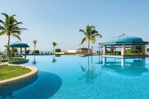 a pool at a resort with palm trees and a gazebo at Wyndham Garden Salalah Mirbat in Salalah