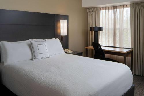 ein Hotelzimmer mit einem großen weißen Bett und einem Schreibtisch in der Unterkunft Sonesta ES Suites Fairfax Fair Lakes in Fairfax