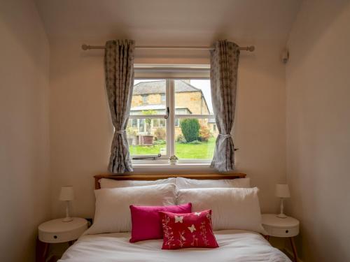 莫頓因馬什的住宿－Pass the Keys Secluded 2 bedroom cottage in scenic Aston Magna，一间卧室配有带两个枕头的床和窗户