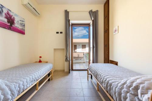 2 camas en una habitación con ventana en Appartamenti Verdemare by BarbarHouse, en Torre San Giovanni