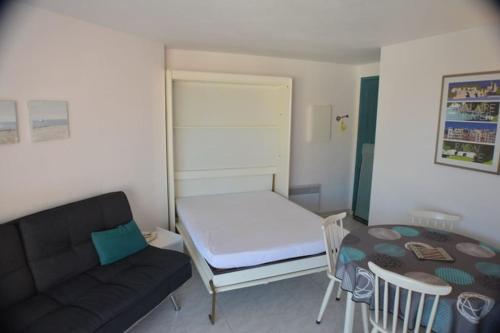 Cette petite chambre comprend un canapé et une table. dans l'établissement Bel Appartement 2 pièces 200m Plages, à Cavalaire-sur-Mer