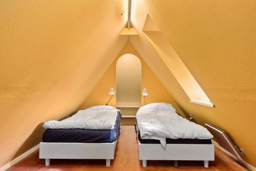 two beds in a room with yellow walls at Skrædderens Hus in Horsens