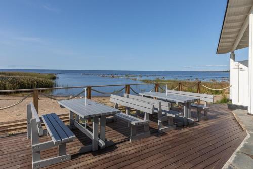 eine Terrasse mit Picknicktischen und Bänken am Strand in der Unterkunft Raahe Apartments in Raahe